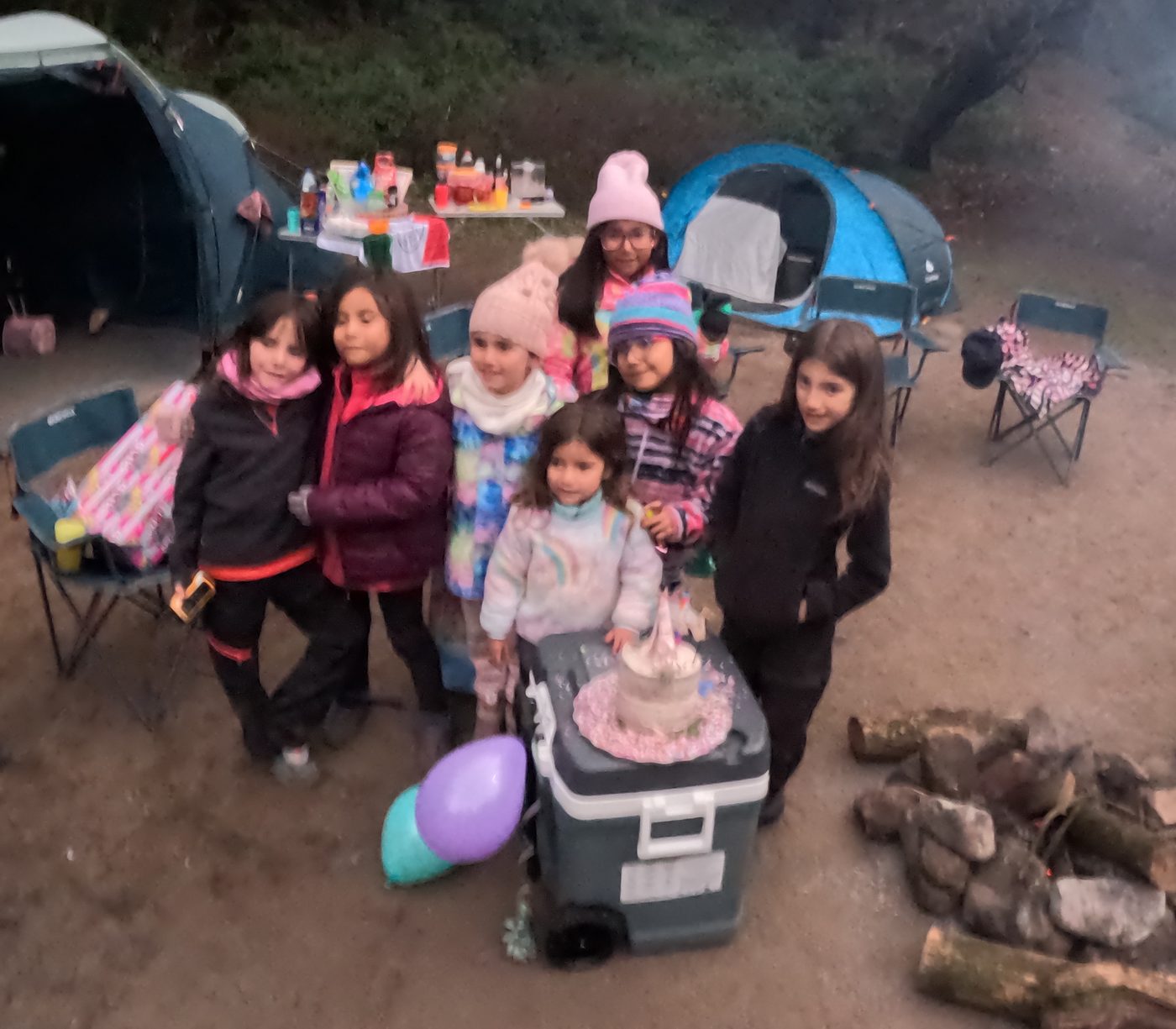 Grupo de niñas junto al pastel de cumpleaños en el campamento